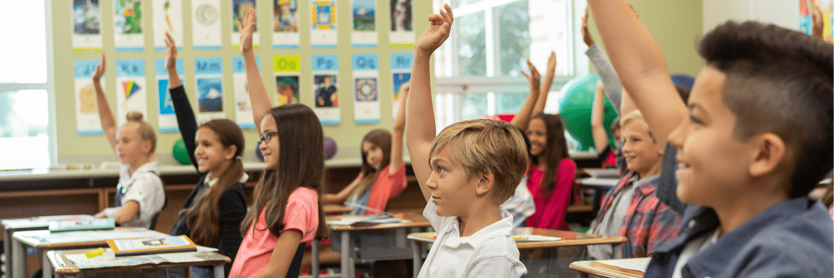 Studies Weekly Students Raising Hands Students in a classroom raising their hands