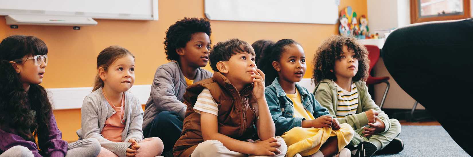 Group of students sitting on the floor of the classroom paying attention