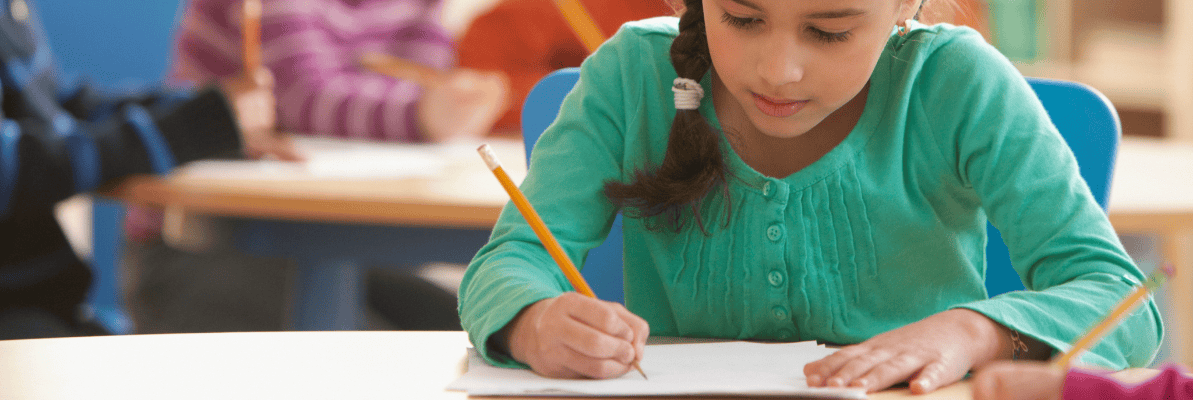 Hispanic Girl Student Student writing in a notebook at a desk