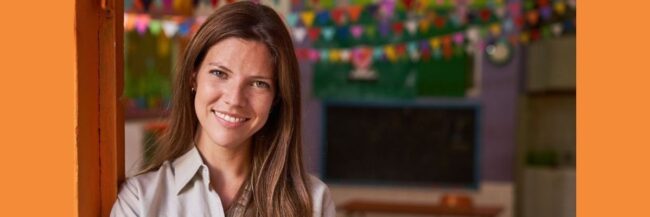 Happy Teacher Standing in Classroom Doorway