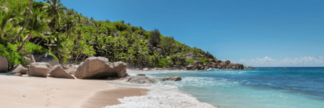 Beach with blue sky, waves, and rocks