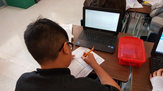 Student filling out graphic organizer Studies Weekly Spotlight