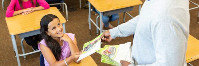 SW-4806.jpg Studies weekly teacher handing a Studies Weekly newspaper to a student