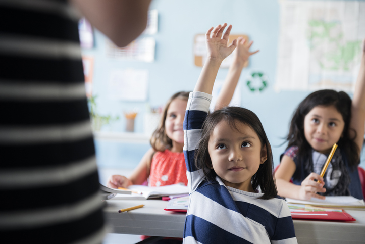 Students raise their hands, following class rules during the the second half of the school year.