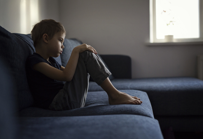 Boy sitting in sofa Lonely boy at home because of pandemic