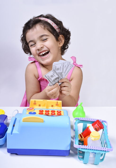 Happy Cashier Girl playing with toy register as part of arly childhood education