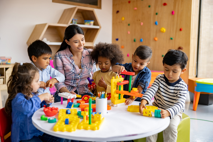 Teacher with a group of elementary students playing with toy blocks Children participating in arly childhood education