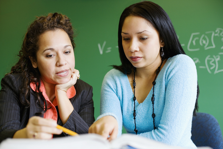 Teacher teaching student in classroom New teacher meets with her mentor to improve instruction.