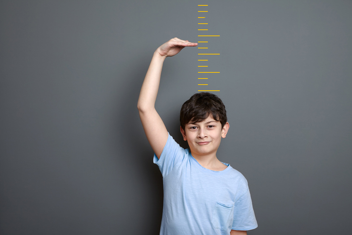 Cute boy is showing height on a wall scale Boy measures his height to illustrate a growth mindset