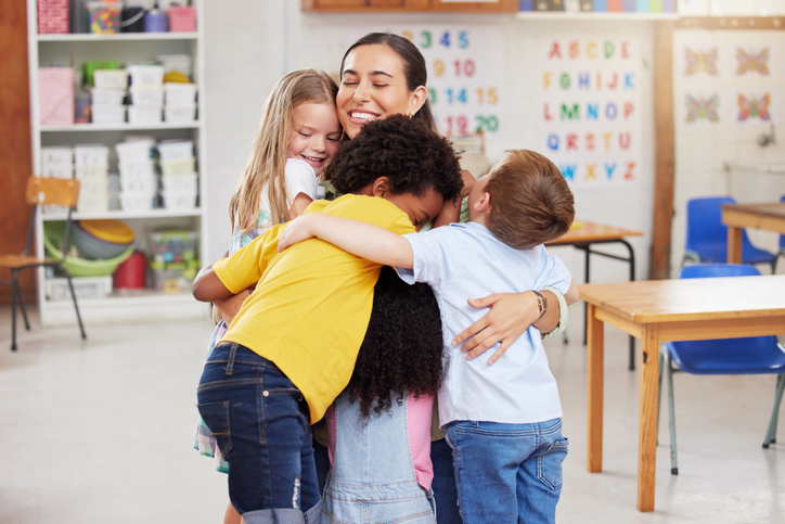 Shot of a woman hugging her learners Teacher hugs her students as part of promoting student well-being