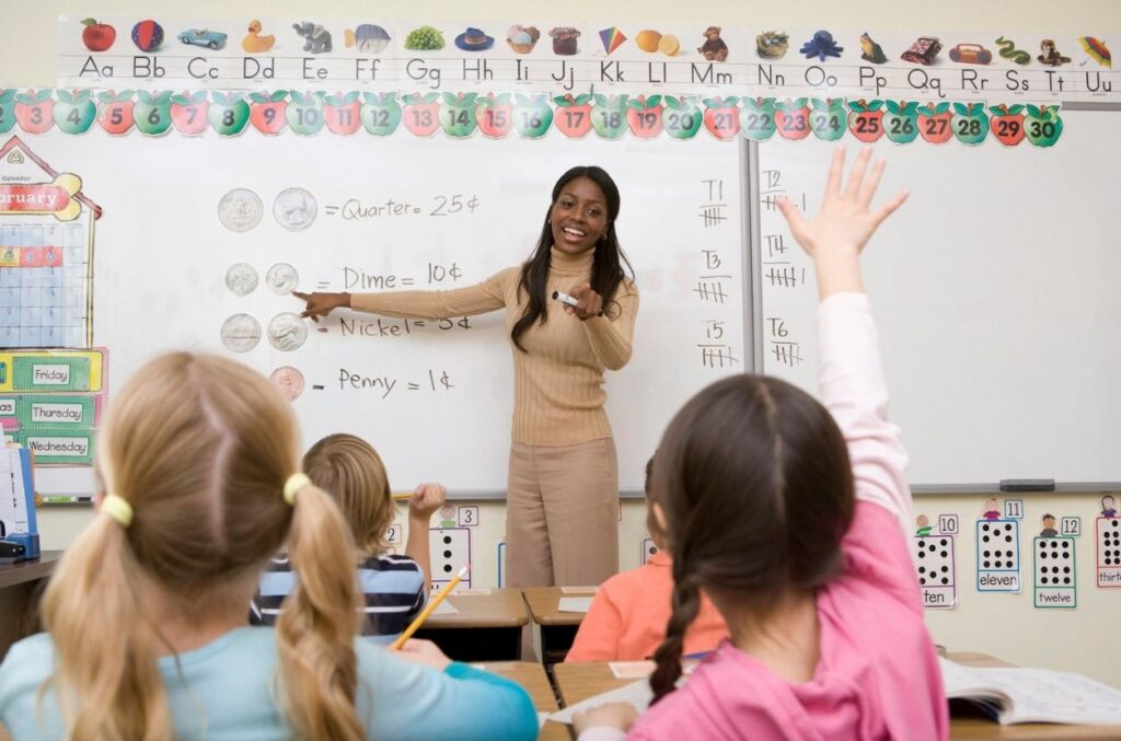 Teacher teaching math to students Elementary teacher points to student raising their hand