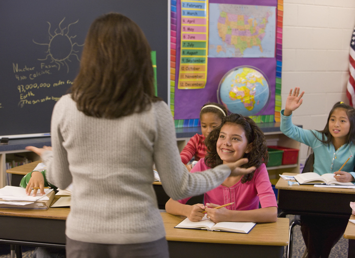 Teacher talking to students in classroom Elementary school teacher teaches social studies
