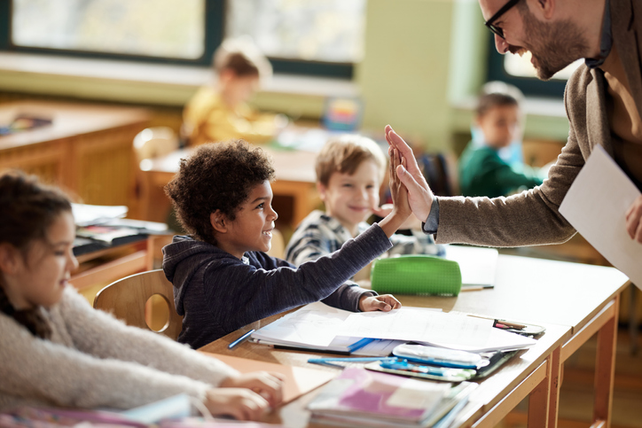 Happy teacher and schoolboy giving each other high-five on a class. Happy teacher and student