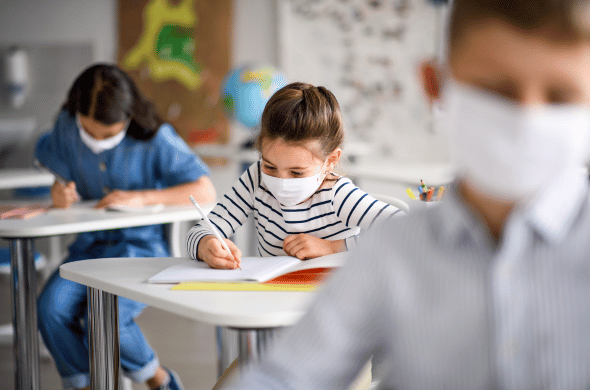 Kids with masks during the COVID-19 pandemic doing work in a classroom