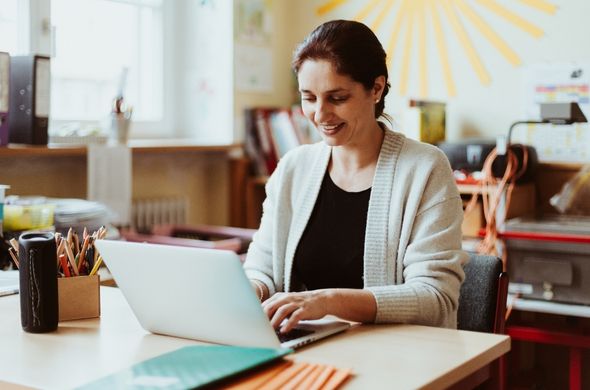 Smiling teacher using a laptop