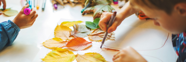 Children doing play-based fall activities with fall leaves