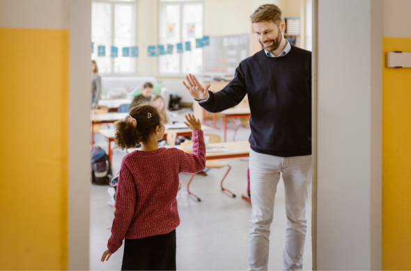 Teacher welcoming and high-fiving student as she enters the classroom