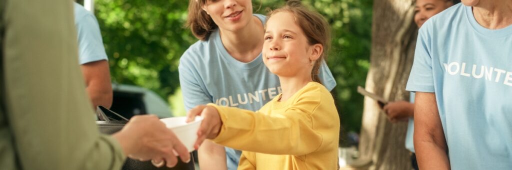 A young girl helps serve food at a volunteer event