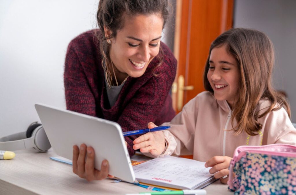 Parent and child doing homework Parent sitting at desk with their student working on homework together