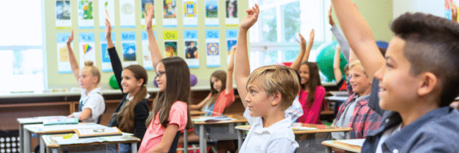 Students raising hands Studies Weekly students raising their hands to answer a question