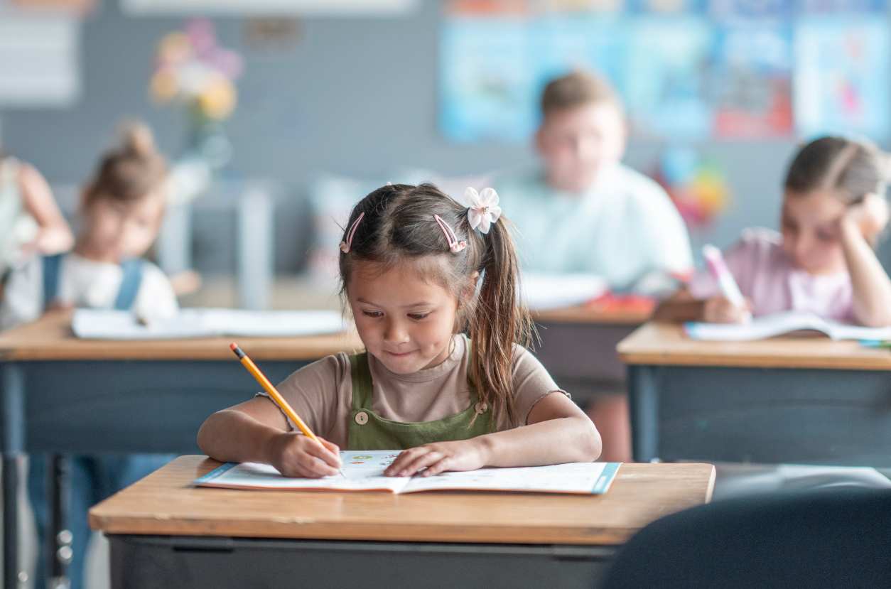 Child working independently Little girl sitting at a desk writing in a workbook