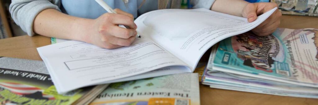 Studies Weekly Funding Options Teacher writing in Teacher Edition at desk