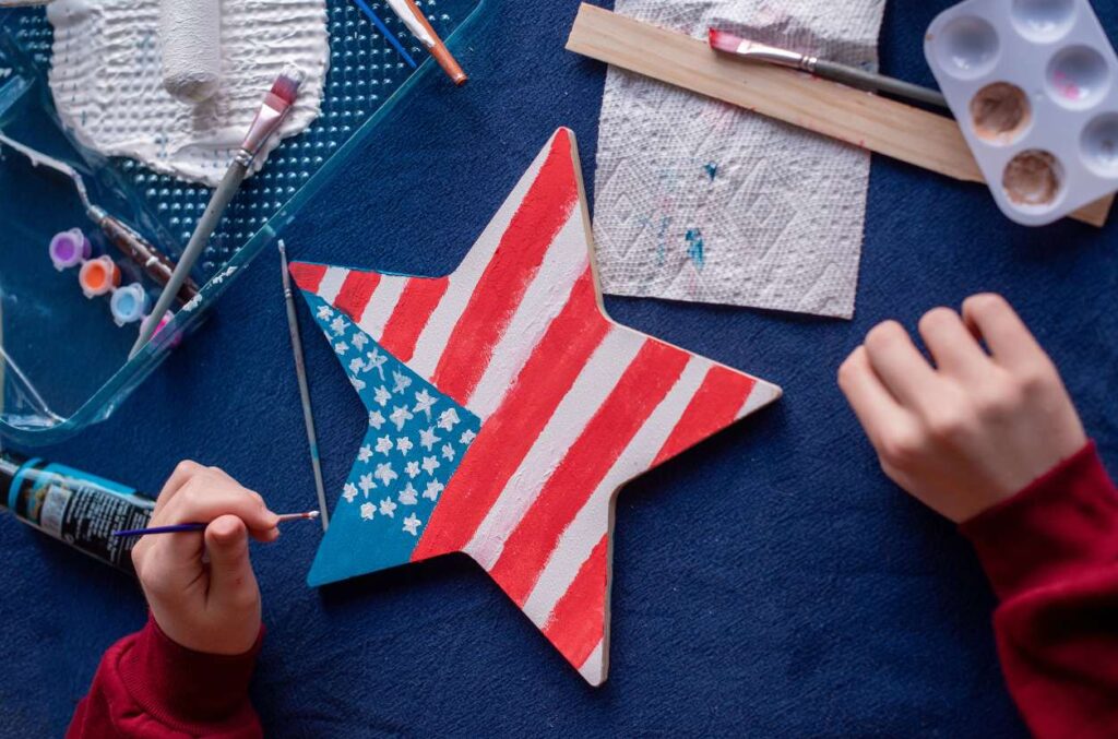 American Symbols Art Activity Child painting the American flag on a wood star