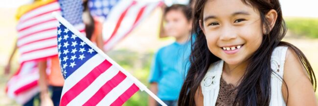 A young girl smiling and holding an American flag for Constitution Day