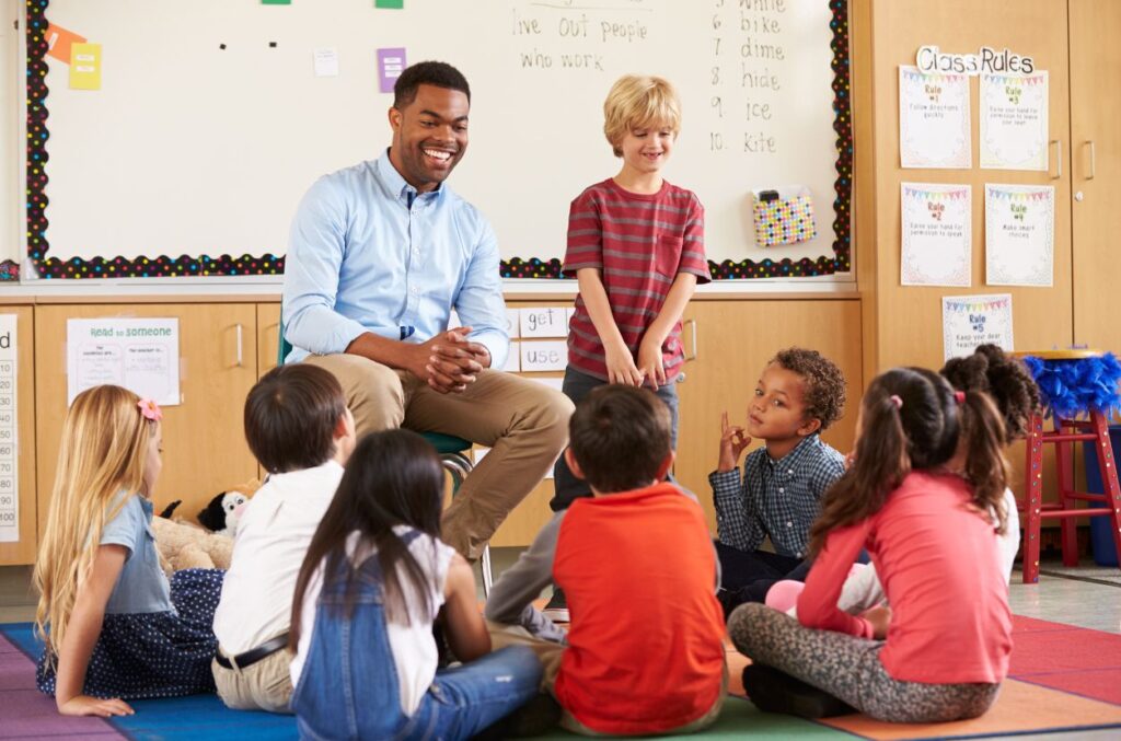 Teacher working with students Teacher sitting at the front of the classroom teaching a group of students