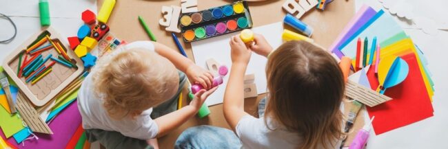 Preschoolers playing Two preschool children painting and sitting around arts and crafts supplies