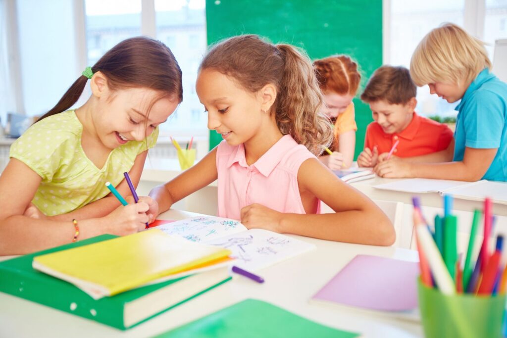 Friends sharing Two friends showing kindness by sharing markers and coloring together in school