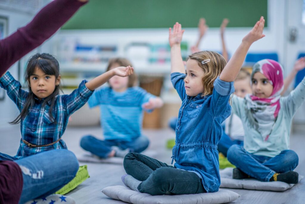 Calming stretches Students sitting on the floor stretching their arms up to the sky to feel calm before a test