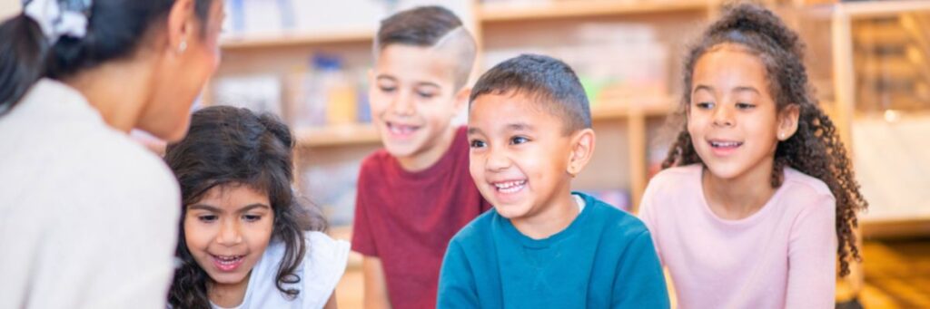Happy students who are emergent bilinguals listening to their teacher