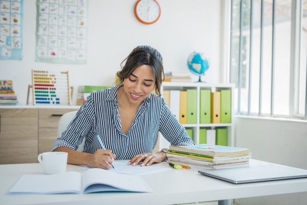 Teacher planning and working Teacher working at her desk writing in her teacher's book
