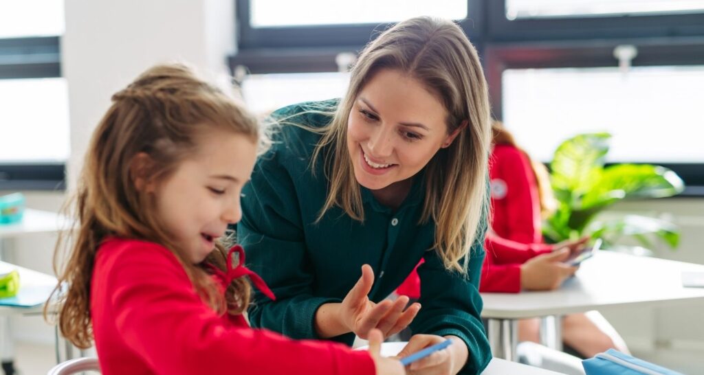 Teacher talking with a student Teacher sitting with a student helping them learn.
