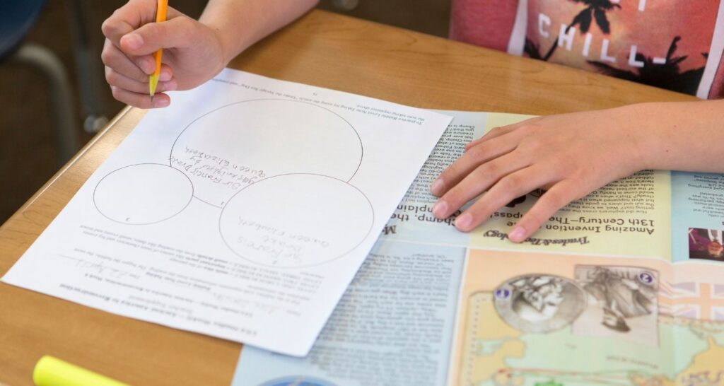 Student filling out a graphic organizer with the Studies Weekly student edition