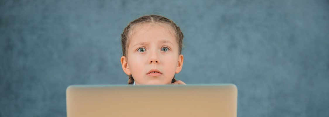 How do I order Studies Weekly Confused schoolgirl with braids sitting in front of grey laptop isolated on grey background.